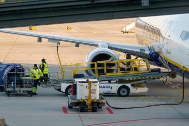 Krakow, Polonya - 20 Ekim 2024 Krakow Havaalanı. Kalkıştan önce uçak kontrolleri (biniş). Havaalanı çalışanı uçağa servis yapıyor. Bagaj yükleme (boşaltma). Yolcular biniyor (varıyor).