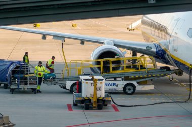 Krakow, Polonya - 20 Ekim 2024 Krakow Havaalanı. Kalkıştan önce uçak kontrolleri (biniş). Havaalanı çalışanı uçağa servis yapıyor. Bagaj yükleme (boşaltma). Yolcular biniyor (varıyor).