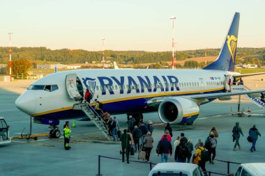 Krakow, Polonya - 20 Ekim 2024 Krakow Havaalanı. Kalkıştan önce uçak kontrolleri (biniş). Havaalanı çalışanı uçağa servis yapıyor. Bagaj yükleme (boşaltma). Yolcular biniyor (varıyor).