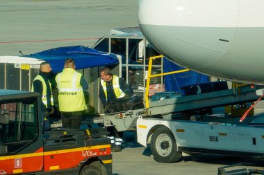 Krakow, Polonya - 20 Ekim 2024 Krakow Havaalanı. Kalkıştan önce uçak kontrolleri (biniş). Havaalanı çalışanı uçağa servis yapıyor. Bagaj yükleme (boşaltma). Yolcular biniyor (varıyor).