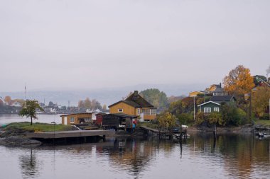Oslo, Norveç - 20 Ekim 2024: Oslofjord (Oslofjorden), yazlık ev ve yazlık ev manzarası. Evleri eğlence için çerçevelet. Ormanın ve kayaların arasında bir kulübe. Çok renkli özel evler.