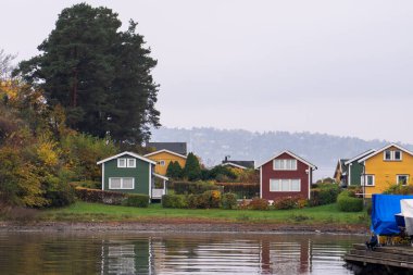 Oslo, Norveç - 20 Ekim 2024: Oslofjord (Oslofjorden), yazlık ev ve yazlık ev manzarası. Evleri eğlence için çerçevelet. Ormanın ve kayaların arasında bir kulübe. Çok renkli özel evler.