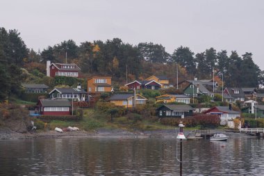 Oslo, Norveç - 20 Ekim 2024: Oslofjord (Oslofjorden), yazlık ev ve yazlık ev manzarası. Evleri eğlence için çerçevelet. Ormanın ve kayaların arasında bir kulübe. Çok renkli özel evler.