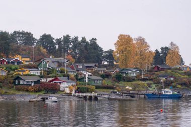 Oslo, Norveç - 20 Ekim 2024: Oslofjord (Oslofjorden), yazlık ev ve yazlık ev manzarası. Evleri eğlence için çerçevelet. Ormanın ve kayaların arasında bir kulübe. Çok renkli özel evler.