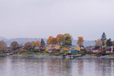 Oslo, Norveç - 20 Ekim 2024: Oslofjord (Oslofjorden), yazlık ev ve yazlık ev manzarası. Evleri eğlence için çerçevelet. Ormanın ve kayaların arasında bir kulübe. Çok renkli özel evler.