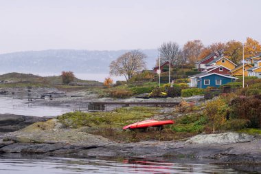 Oslo, Norveç - 20 Ekim 2024: Oslofjord (Oslofjorden), yazlık ev ve yazlık ev manzarası. Evleri eğlence için çerçevelet. Ormanın ve kayaların arasında bir kulübe. Çok renkli özel evler.