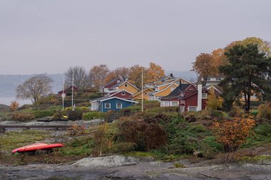 Oslo, Norveç - 20 Ekim 2024: Oslofjord (Oslofjorden), yazlık ev ve yazlık ev manzarası. Evleri eğlence için çerçevelet. Ormanın ve kayaların arasında bir kulübe. Çok renkli özel evler.