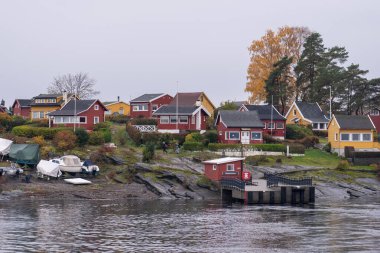 Oslo, Norveç - 20 Ekim 2024: Oslofjord (Oslofjorden), yazlık ev ve yazlık ev manzarası. Evleri eğlence için çerçevelet. Ormanın ve kayaların arasında bir kulübe. Çok renkli özel evler.