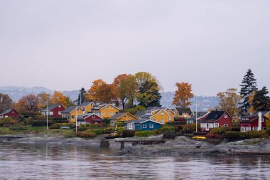 Oslo, Norveç - 20 Ekim 2024: Oslofjord (Oslofjorden), yazlık ev ve yazlık ev manzarası. Evleri eğlence için çerçevelet. Ormanın ve kayaların arasında bir kulübe. Çok renkli özel evler.