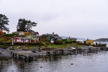 Oslo, Norveç - 20 Ekim 2024: Oslofjord (Oslofjorden), yazlık ev ve yazlık ev manzarası. Evleri eğlence için çerçevelet. Ormanın ve kayaların arasında bir kulübe. Çok renkli özel evler.