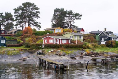 Oslo, Norveç - 20 Ekim 2024: Oslofjord (Oslofjorden), yazlık ev ve yazlık ev manzarası. Evleri eğlence için çerçevelet. Ormanın ve kayaların arasında bir kulübe. Çok renkli özel evler.