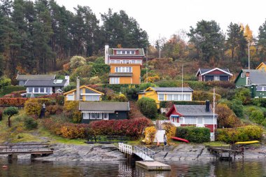 Oslo, Norveç - 20 Ekim 2024: Oslofjord (Oslofjorden), yazlık ev ve yazlık ev manzarası. Evleri eğlence için çerçevelet. Ormanın ve kayaların arasında bir kulübe. Çok renkli özel evler.