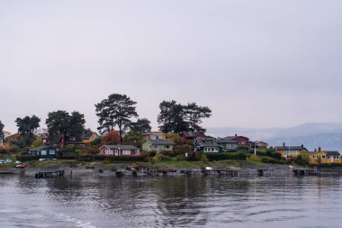 Oslo, Norveç - 20 Ekim 2024: Oslofjord (Oslofjorden), yazlık ev ve yazlık ev manzarası. Evleri eğlence için çerçevelet. Ormanın ve kayaların arasında bir kulübe. Çok renkli özel evler.
