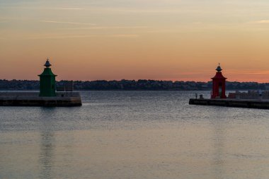 Piran, Slovenia - November 3, 2024: Red lighthouse against the sea. Evening sunset in the port city. Lighthouse with rocks in the water. clipart