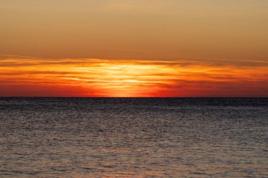 Piran, Slovenya - 3 Kasım 2024: Denizde harika bir gün batımı. Sakin bir denizin arka planında gün batımı. Güneş deniz ufkunun arkasında batıyor..