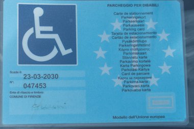 Florence, İtalya - 5 Kasım 2024: Sürücüler için engelli kimliği. Arabanın penceresinin altındaki engelli işareti.
