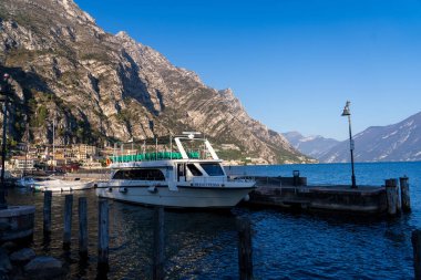 Limone Sul Garda, İtalya - 7 Kasım 2024: Garda Gölü ve dağların manzarası. Rıhtımdaki eğlence teknesi.