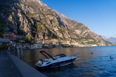 Limone Sul Garda, İtalya - 7 Kasım 2024: Garda Gölü ve dağların manzarası. Rıhtımdaki eğlence teknesi.