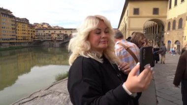 Florence, İtalya - 5 Kasım 2024: Bir kız Eski Köprü önünde selfie çekiyor (The Ponte Vecchio)