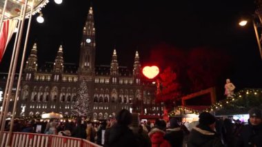 Viyana, Avusturya - 13 Aralık 2024: Rathaus Park ve Viyana Belediye Binası akşam manzarası. Noel pazarı. Yeni yıl aydınlanması. Meydandaki insanlar.