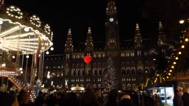 Viyana, Avusturya - 13 Aralık 2024: Rathaus Park ve Viyana Belediye Binası akşam manzarası. Noel pazarı. Yeni yıl aydınlanması. Meydandaki insanlar.