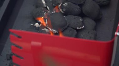 Sıcak bir açık verandada kırmızı bir mangal mangalı kurulur. Yakınlarda gerekli ızgara araçları ve gaz lambası, çakmak gazı, briketler gibi kullanıma hazır eşyalar bulunuyor..