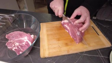 Bir adam barbekü için biftek kesiyor. Izgara için marine edilmiş et hazırlanıyor..