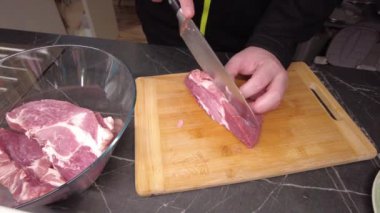 Bir adam barbekü için biftek kesiyor. Izgara için marine edilmiş et hazırlanıyor..