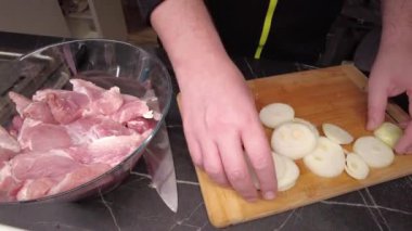 Bir adam barbekü için biftek kesiyor. Izgara için marine edilmiş et hazırlanıyor..