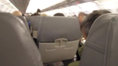 Viyana, Avusturya - 18 Ocak 2025: Uçağın içinde yolcu alımı. El bagajı başlık kutusuna konur. Bir uçuş görevlisi uçağa binerken yolcuya yardım eder..