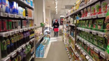 Bükreş, Romanya 18 Ocak 2025: Bir müşteri bir mağazadan ürün seçiyor. Dükkanda malı olan tezgahlar.