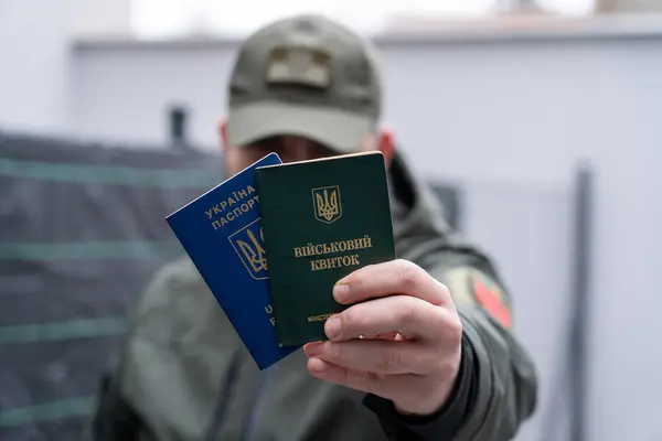 Ukrayna askeri kimliği ve Ukrayna pasaportu bir askerin elinde. Üniformalı bir adam elinde Ukrayna pasaportu ve askeri kimlik tutuyor. Ukraynalı askerler için yurt dışına seyahat.