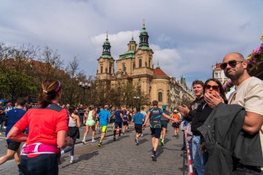 Prag, Çek Cumhuriyeti - 5 Nisan 2025: Generali Half Marathon Prag 2025. İnsanlar maraton koşuyor. Koşucu yelpazeyi eliyle selamlar. İnsanlar bir koşucunun avucunu çırpar.