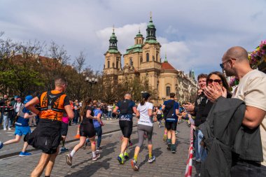 Prag, Çek Cumhuriyeti - 5 Nisan 2025: Generali Half Marathon Prag 2025. İnsanlar maraton koşuyor. Koşucu yelpazeyi eliyle selamlar. İnsanlar bir koşucunun avucunu çırpar.