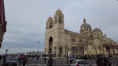 Marsilya, Fransa, 2 Şubat 2025: Çağdaş binaların çerçevelediği modern bir şehir caddesinden alınan La Major Katedrali (Marsilya Katedrali) manzarası. Katedralin görkemli mimarisi.