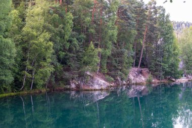 Adrspach, Çek Cumhuriyeti - 20.07.2025: Piskovna Gölü 'ndeki Adrspach-Teplice Kayaları manzarası. Ağaçların ve kayaların arasında bir orman gölü.