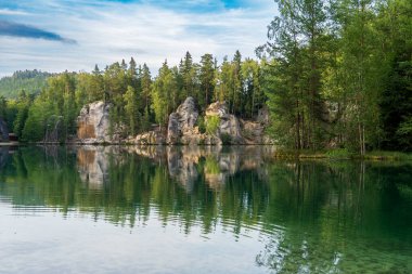 Adrspach, Çek Cumhuriyeti - 20.07.2025: Piskovna Gölü 'ndeki Adrspach-Teplice Kayaları manzarası. Ağaçların ve kayaların arasında bir orman gölü.