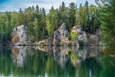 Adrspach, Çek Cumhuriyeti - 20.07.2025: Piskovna Gölü 'ndeki Adrspach-Teplice Kayaları manzarası. Ağaçların ve kayaların arasında bir orman gölü.