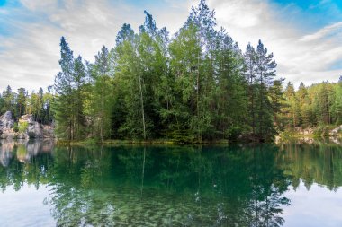 Adrspach, Çek Cumhuriyeti - 20.07.2025: Piskovna Gölü 'ndeki Adrspach-Teplice Kayaları manzarası. Ağaçların ve kayaların arasında bir orman gölü.