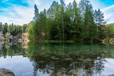 Adrspach, Çek Cumhuriyeti - 20.07.2025: Piskovna Gölü 'ndeki Adrspach-Teplice Kayaları manzarası. Ağaçların ve kayaların arasında bir orman gölü.