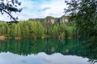 Adrspach, Çek Cumhuriyeti - 20.07.2025: Piskovna Gölü 'ndeki Adrspach-Teplice Kayaları manzarası. Ağaçların ve kayaların arasında bir orman gölü.