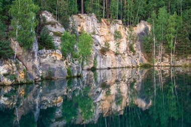 Adrspach, Çek Cumhuriyeti - 20.07.2025: Piskovna Gölü 'ndeki Adrspach-Teplice Kayaları manzarası. Ağaçların ve kayaların arasında bir orman gölü.