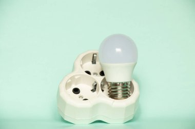LED ampul mavi arka planda üçlü bir sokette duruyor, elektrik ve ışık tasarrufu sağlıyor.