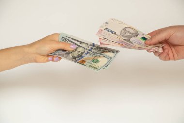 Beyaz bir zemin üzerinde 500 dolar ve 200 hryvniaya karşılık 100 dolar değiş tokuş, para, iş ve finans