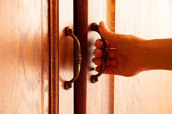 Женская рука оторвала старый деревянный шкаф, открыла дверь бельевого шкафа, ручка на дверях на мебели
