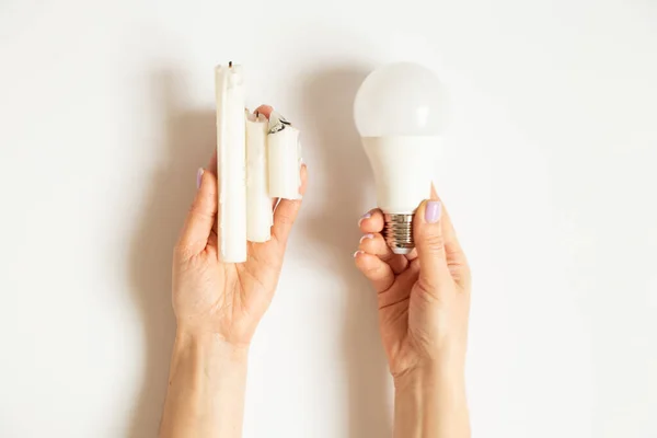 LED light bulb and candles in the hands of a girl on a white background, electricity and savings choice, no light