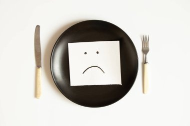 Üzücü bir ifade kağıda çizilir, beyaz arka planda bir tabağa uzanır, üzüntü ve yiyecek yoktur.