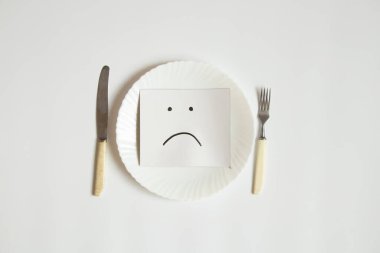 Üzücü bir ifade kağıda çizilir, beyaz arka planda bir tabağa uzanır, üzüntü ve yiyecek yoktur.