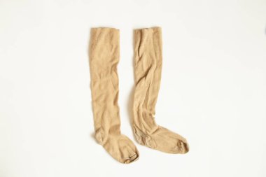 Kahverengi uzun çoraplar beyaz arka planda otluyor.