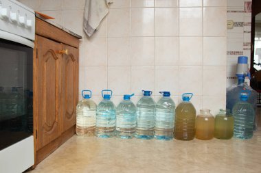 Ukrayna 'da bir evin zemininde su bulunan plastik şişeler, Ukrayna' daki roket saldırıları sırasında su kaynaklı su dolu şişeler, susuz ve ışıksız.